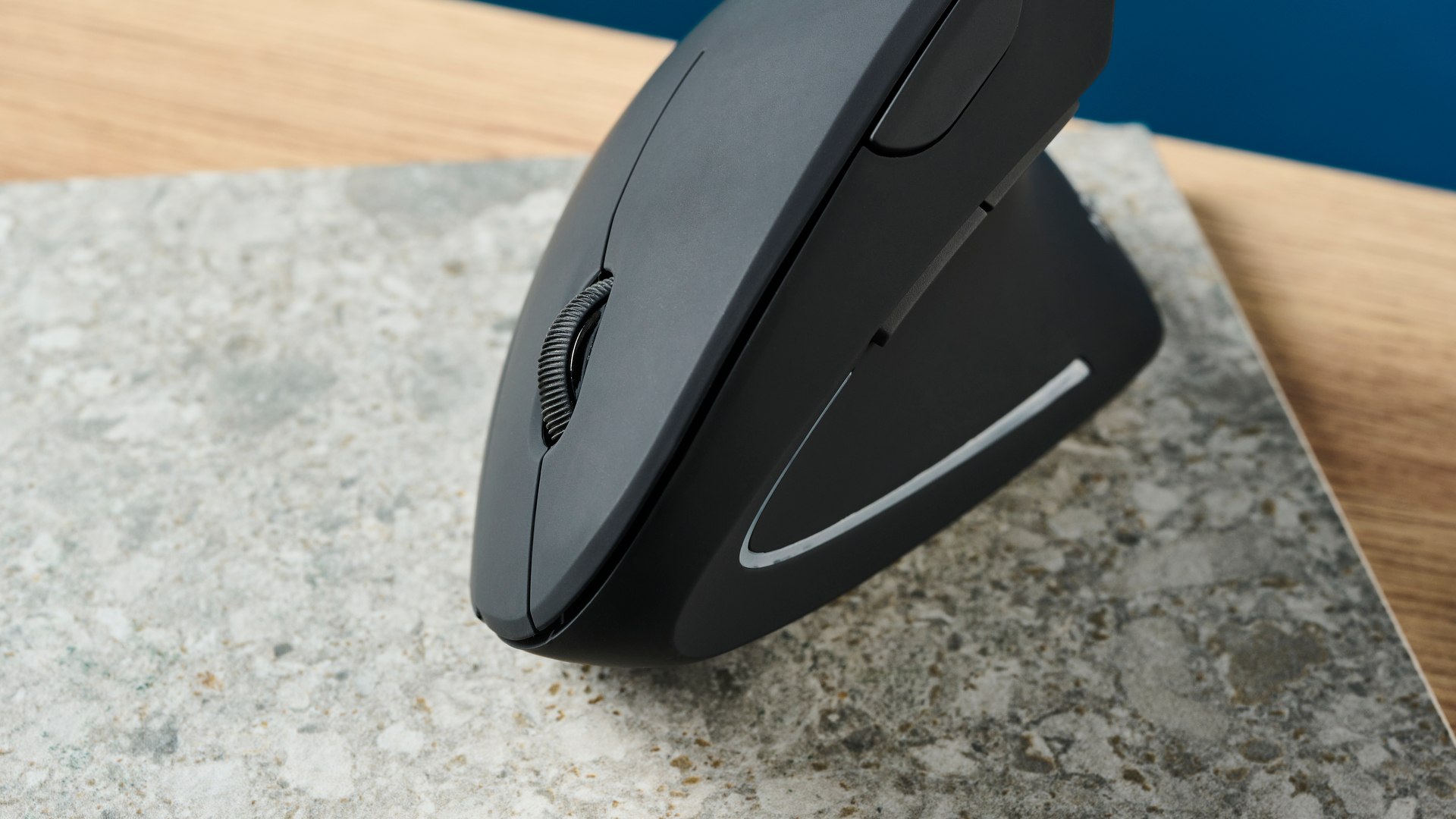 De Anker 2.4G Wireless Vertical Ergonomic Mouse op een stenen oppervlak met een blauwe muur op de achtergrond